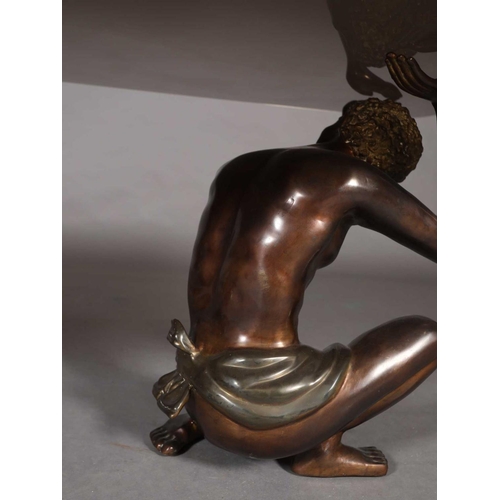60 - A glass coffee table, rectangular, raised on two bronzed metal figures of crouching Nubian males, 15... 