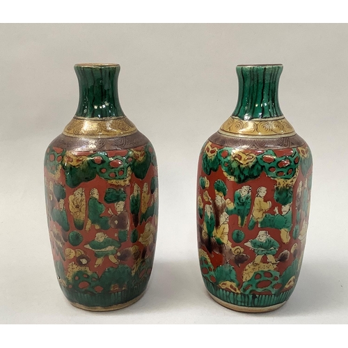 32 - A pair of Japanese pottery vases of hexagonal outline, the buff ground painted with multiple figures... 