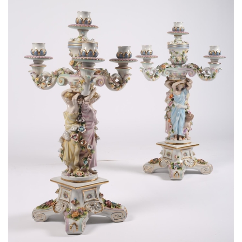 102 - A PAIR OF CONTINENTAL PORCELAIN FLOWER ENCRUSTED FIVE BRANCH CANDELABRA each with figural central co... 