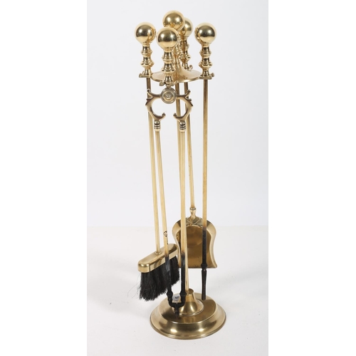 103 - A BRASS FOUR PIECE COMPANION SET ON STAND comprising tongs shovel poker and brush each with a knoppe... 