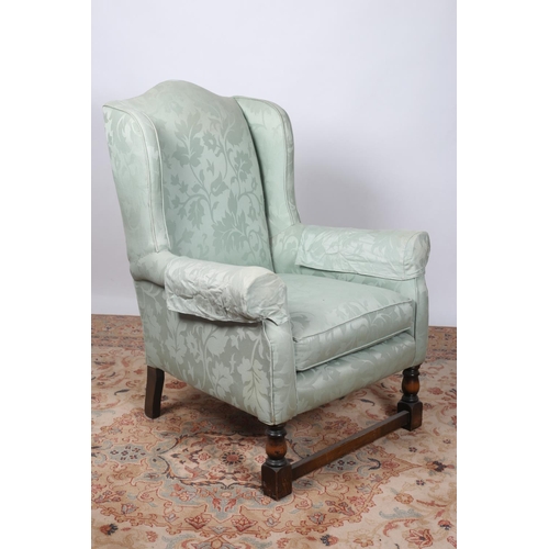 17 - AN OAK FRAME AND UPHOLSTERED WING CHAIR with loose cushion and scroll arms on baluster and square su... 