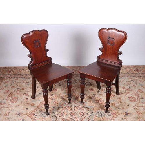 52 - A PAIR OF VICTORIAN MAHOGANY HALL CHAIRS each with a shield shaped back and panelled seat on baluste... 