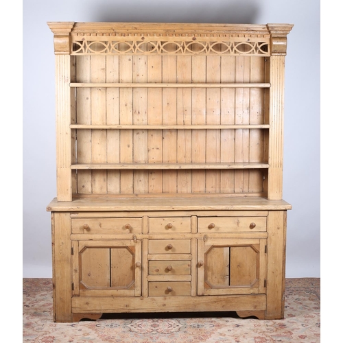 63 - A VINTAGE PINE DRESSER the pierced and moulded cornice above four open shelves between fluted pilast... 