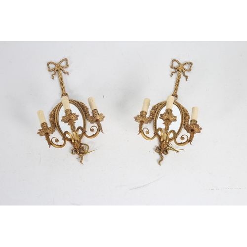 576 - A PAIR OF CONTINENTAL GILT BRASS GIRANDOLE MIRRORS each with a ribbon tied back plate the oval plate... 