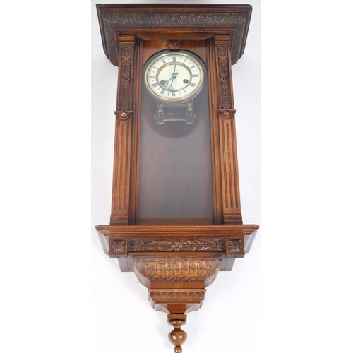 586 - AN EDWARDIAN MAHOGANY WALL CLOCK the carved hood above a rectangular arched glazed door between reed... 