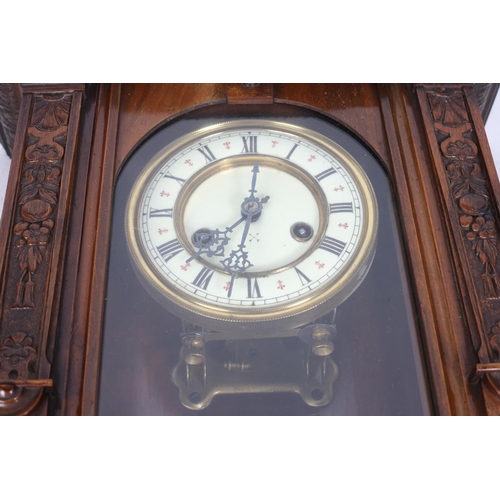 586 - AN EDWARDIAN MAHOGANY WALL CLOCK the carved hood above a rectangular arched glazed door between reed... 