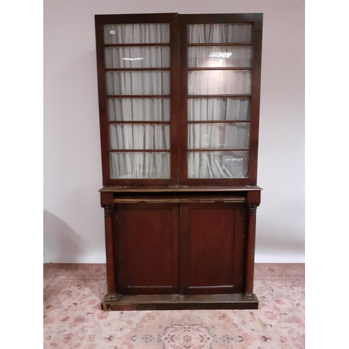 597 - A 19TH CENTURY MAHOGANY BOOKCASE the glazed doors containing shelves the base with cupboards between... 