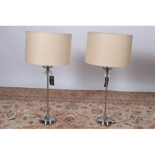 89 - A PAIR OF CONTEMPORARY WHITE METAL TABLE LAMPS each with a cylindrical and glazed column raised on a... 