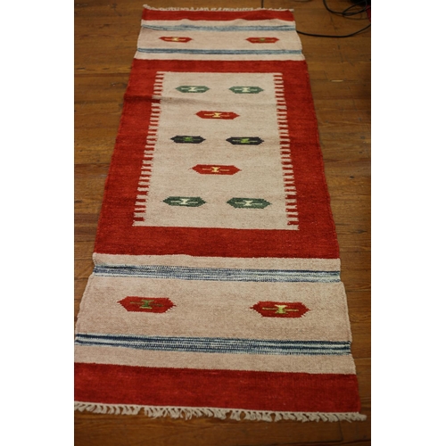 470 - A GABBEH WOOL RUNNER the beige and red ground with diamond shaped panels and blue stripes 243cm x 80... 