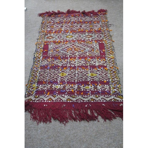 471 - A BERBER MOROCCAN RUG the wine ground with serrated and diamond shaped panels with sequins 155cm x 1... 