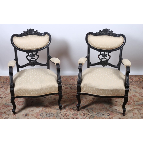 27 - A PAIR OF EDWARDIAN EBONISED AND UPHOLSTERED ARMCHAIRS each with an upholstered back and pierced car... 