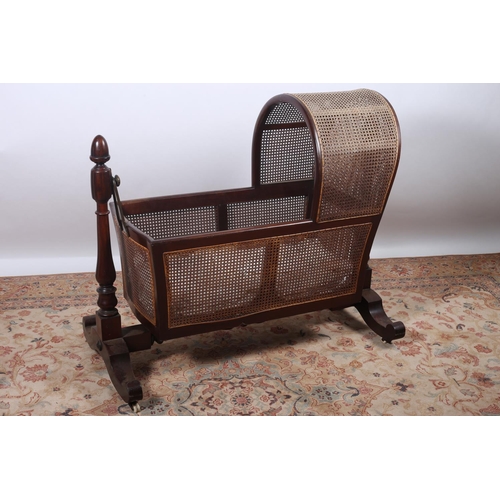 31 - A 19TH CENTURY MAHOGANY CHILD'S CRADLE with bergere panels and domed hood raised on baluster upright... 