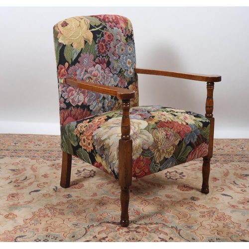 37 - A VINTAGE OAK AND UPHOLSTERED ARMCHAIR the curved arms with baluster arm supports on moulded legs