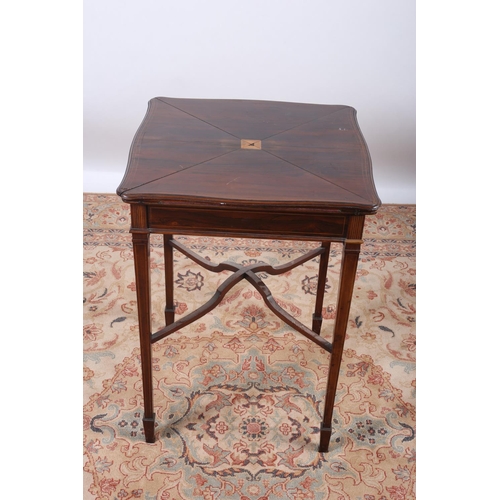 65 - AN EDWARDIAN ROSEWOOD ENVELOPE CARD TABLE of serpentine outline the shaped top with hinged flaps con... 