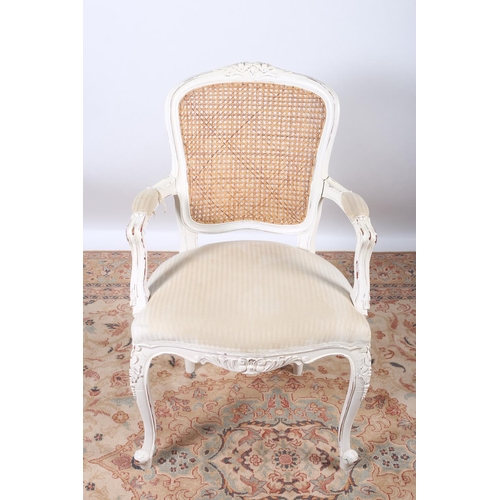 66 - A CONTINENTAL WHITE PAINTED BERGERE AND UPHOLSTERED ARMCHAIR with foliate carved top rail above a be... 