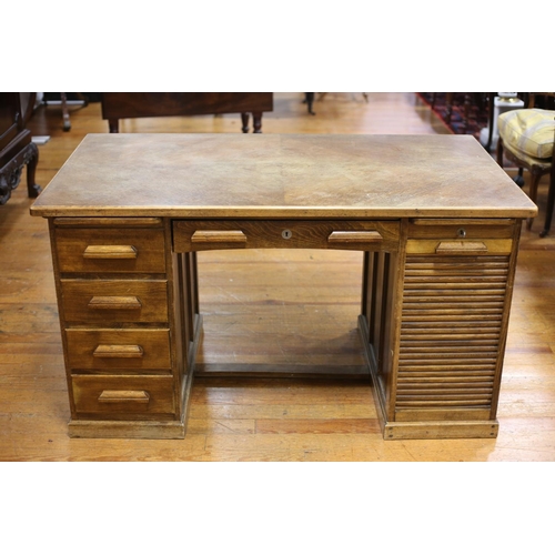 76 - A VINTAGE OAK PEDESTAL DESK of rectangular outline the shaped top with frieze drawer flanked by pede... 