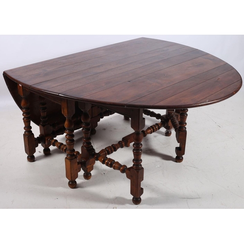 101 - A FINE OAK JACOBEAN DESIGN DROP LEAF TABLE the oval hinged top raised on bobbin turned and square le... 