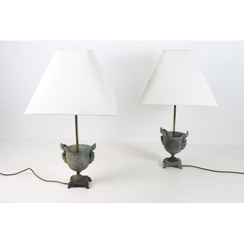 104 - A PAIR OF BRONZE TABLE LAMPS each of urn form with figural mask handles above a circular foot on rec... 