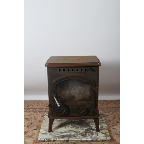 598 - A CAST IRON FREE STANDING SOLID FUEL STOVE of rectangular outline with glazed panel and hinged door ... 