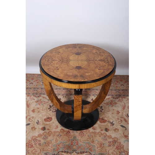 90 - AN ART DECO DESIGN WALNUT AND EBONISED TABLE of circular outline the shaped top raised on U-shaped s... 