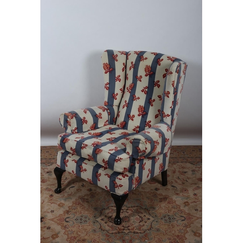 23 - A QUEEN ANNE DESIGN MAHOGANY AND UPHOLSTERED WING CHAIR with scroll over arms and loose cushion on c... 