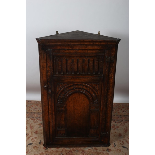 559 - A GOOD GOTHIC DESIGN OAK WALL MOUNTED CORNER CUPBOARD with gothic tracery panelled door containing t... 