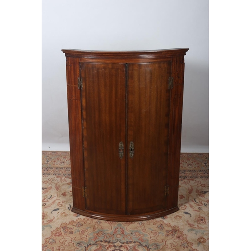 59 - A GEORGIAN MAHOGANY CROSS BANDED HANGING CORNER CUPBOARD the moulded cornice above a pair of panelle... 