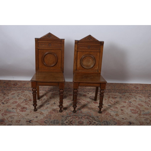 16 - A PAIR OF ARTS AND CRAFTS OAK HALL CHAIRS each with a rectangular shaped back with applied decoratio... 