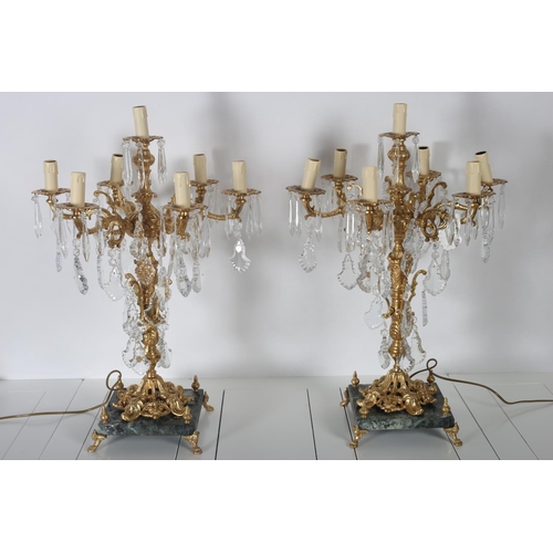 53 - A PAIR OF CONTINENTAL GILT BRASS AND CUT GLASS SEVEN BRANCH CANDELABRA the foliate cast arms hung wi... 