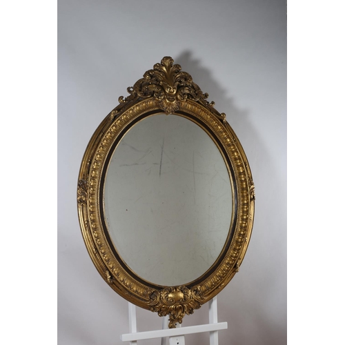 71 - A CONTINENTAL GILT FRAME MIRROR the oval plate within a moulded frame with foliate scroll cresting a... 