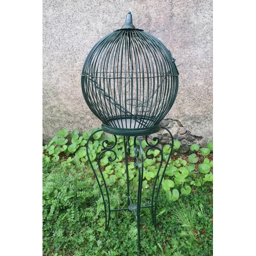 822 - A WROUGHT IRON BIRD CAGE of cylindrical form containing a ladder and feeder raised on C-scroll suppo... 