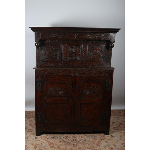 95 - AN EARLY 19TH CENTURY CARVED OAK COURT CUPBOARD the outswept cornice above a carved frieze and carve... 