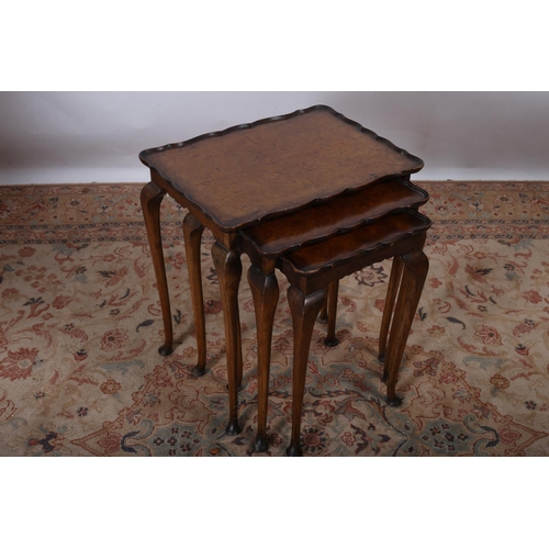 101 - A NEST OF THREE VINTAGE WALNUT TABLES each of serpentine outline the shaped dished tops on cabriole ... 