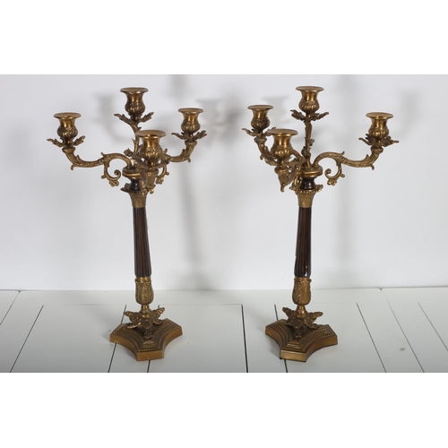 105 - A PAIR OF CONTINENTAL GILT BRASS FOUR BRANCH CANDELABRA with foliate scroll arms and drip pans above... 