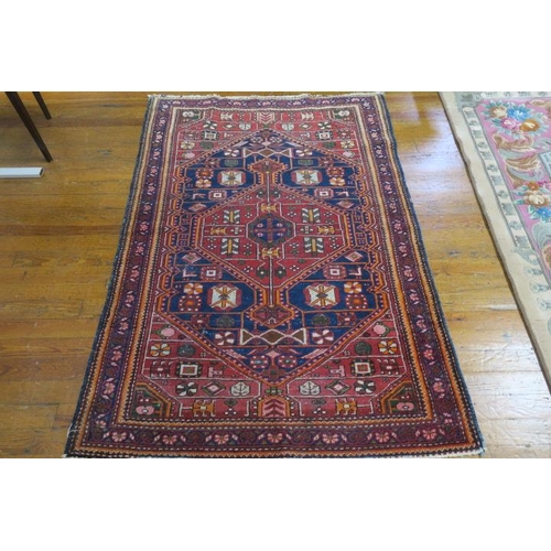 21 - KESHAN WOOL RUG the indigo and wine ground with central panel filled with palmettes hooks and lozeng... 