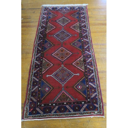 22 - A HAMADAN WOOL RUNNER the wine ground with central diamond shaped panels within a conforming border ... 