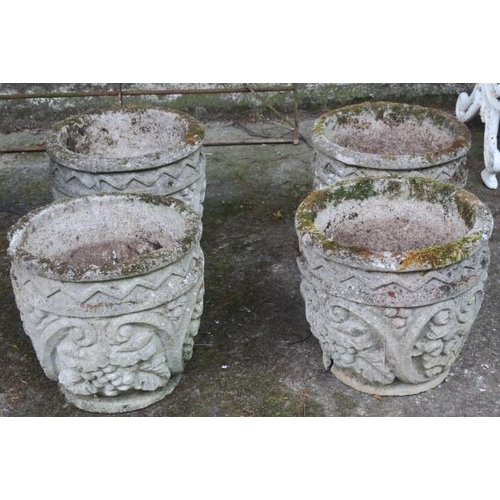 848 - A SET OF FOUR COMPOSITION STONE PLANTERS each of circular tapering form moulded in relief with C-scr... 