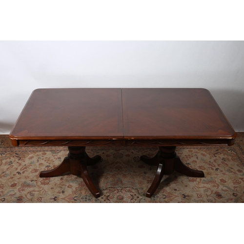 422 - A MAHOGANY CROSS BANDED DINING TABLE of rectangular outline the shaped top with rounded corners rais... 