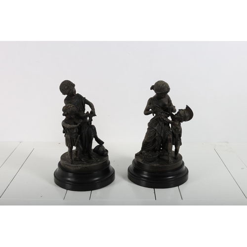 392 - A PAIR OF SPELTER FIGURES modelled as females shown seated with children playing raised on an ebonis... 