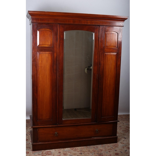 614 - A VINTAGE MAHOGANY WARDROBE the moulded cornice above a bevelled glass mirrored door containing hang... 