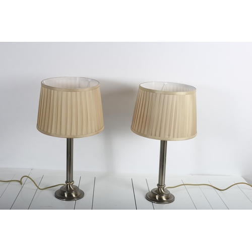 67 - A PAIR OF PLATED TABLE LAMPS each with a reeded column above a circular spreading foot with pleated ... 