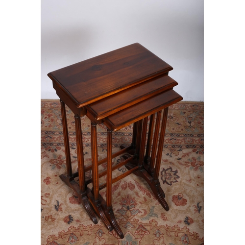 221 - A NEST OF THREE CHERRYWOOD TABLES each of rectangular outline on dual reeded supports on platform ba... 