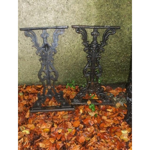 821 - A PAIR OF CAST IRON SUPPORTS with pierced scroll and figural mask decoration raised on a square step... 