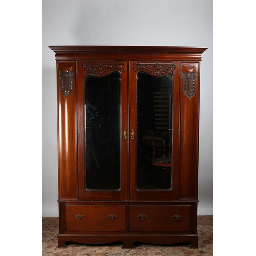 43 - AN EDWARDIAN CARVED MAHOGANY TWO DOOR WARDROBE the moulded cornice above a pair of bevelled glass mi... 
