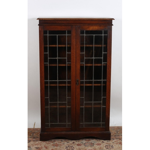 18 - A VINTAGE OAK BOOKCASE of rectangular outline the moulded top above a pair of lead glass and glazed ... 