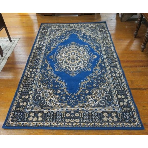 23 - A WOOL RUG the indigo and beige ground with central panel filled with flowerheads and foliage within... 