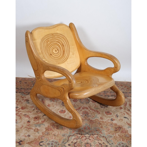 55 - AN ARTS AND CRAFTS PLYWOOD ROCKING CHAIR the rectangular shaped back and seat with scroll arms on mo... 