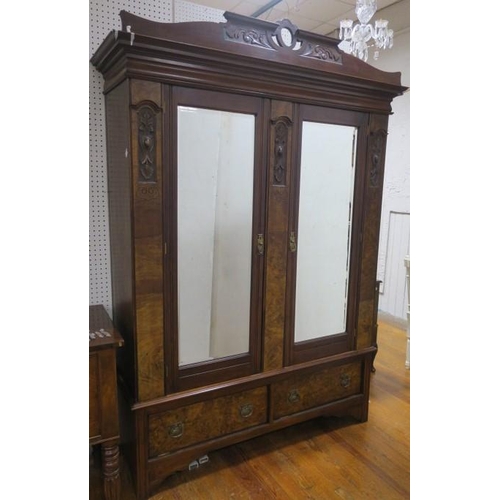 6 - A VINTAGE CARVED MAHOGANY AND WALNUT TWO DOOR WARDROBE the shaped cornice above a pair of bevelled g... 