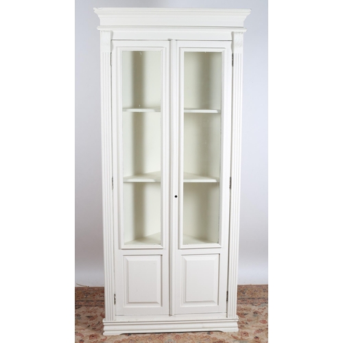 763 - A WHITE PAINTED CORNER CABINET the moulded cornice above a pair of glazed doors with moulded panels ... 