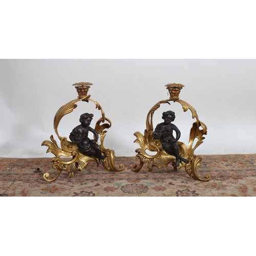 179 - A PAIR OF CONTINENTAL GILT BRASS AND BRONZE CHENETS the foliate cast openwork frames with seated fig... 